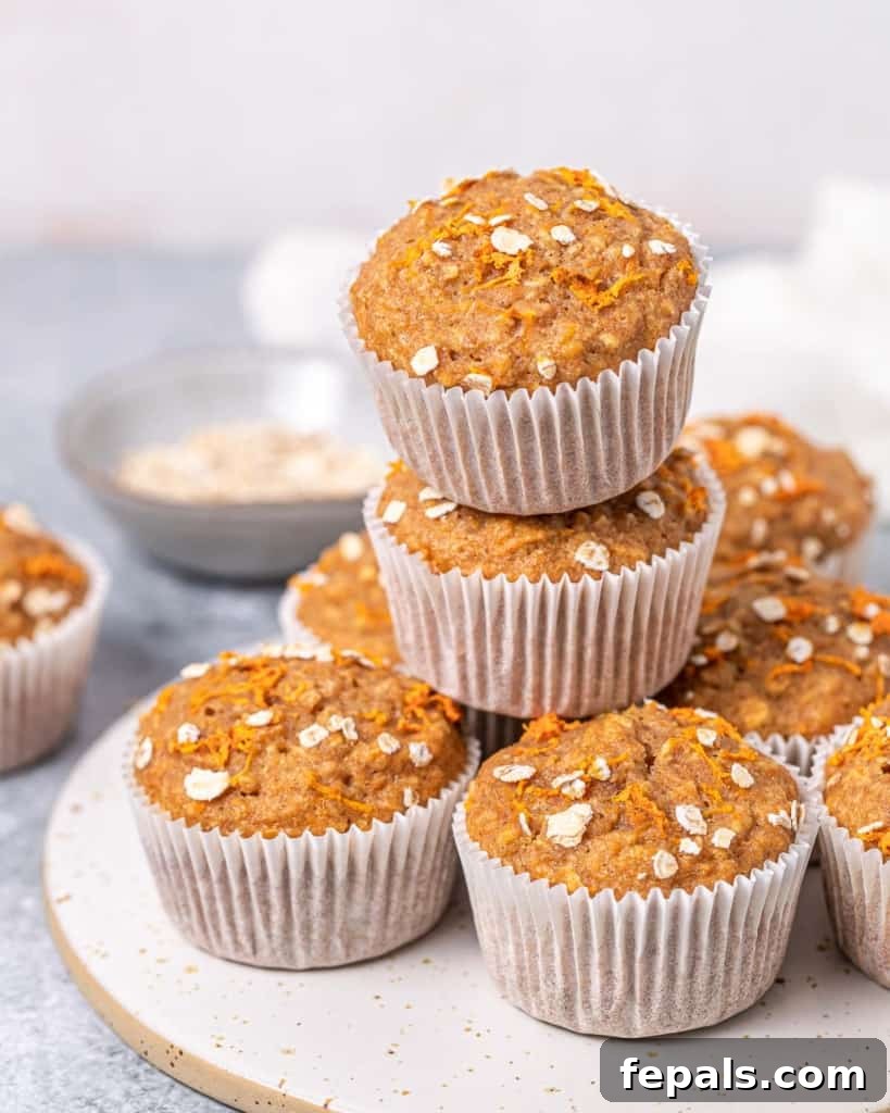 A stack of golden-brown carrot cake muffins, showcasing their soft interior and crumbly top.