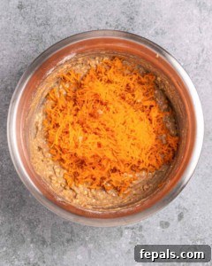 Folding shredded carrots into muffin batter.