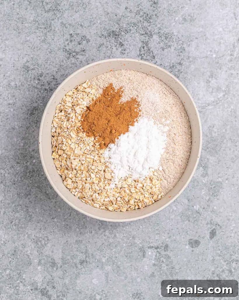 A bowl containing dry ingredients like flour, oats, and spices, ready to be mixed.