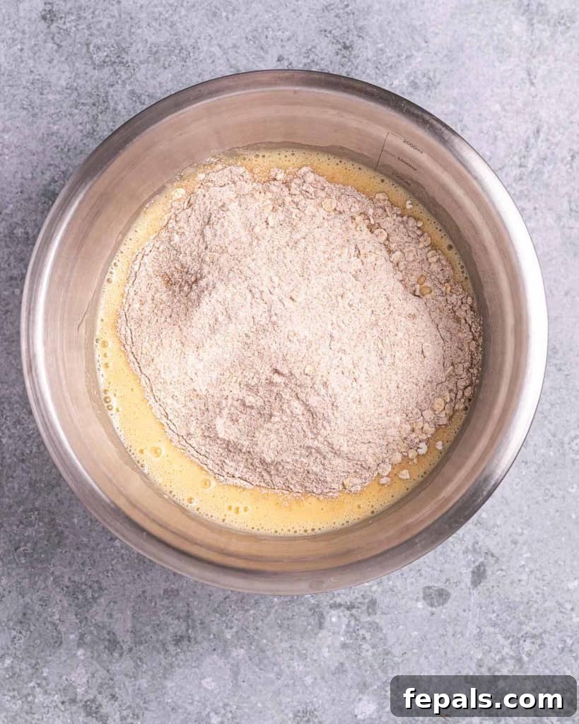 Mixing the flour mixture with the wet ingredients using a spatula.