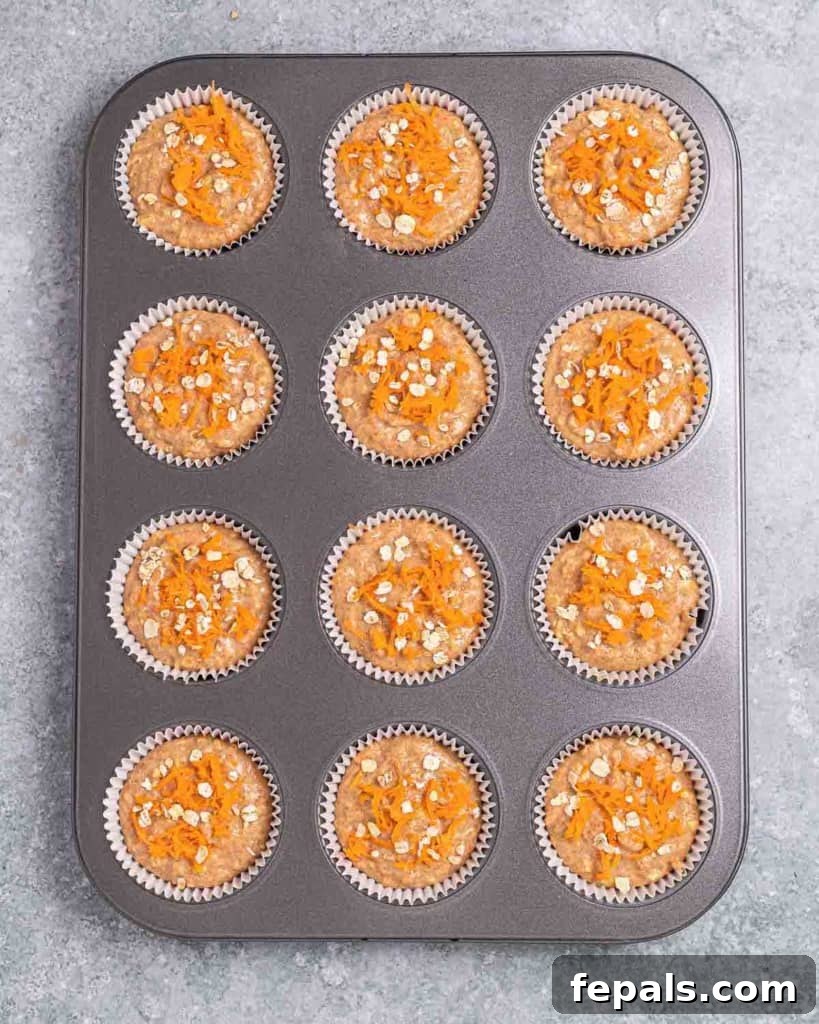 Muffin batter neatly scooped into paper-lined muffin cups in a baking pan, ready for the oven.
