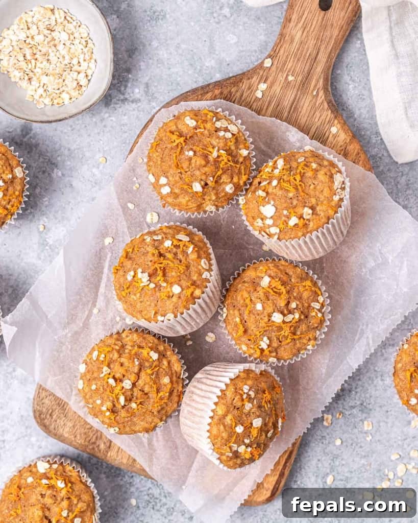 Baked carrot muffins resting on a parchment-lined cutting board, ready to be enjoyed.
