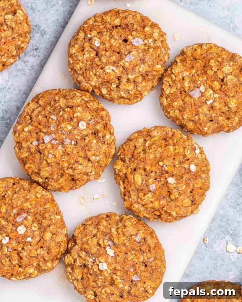 A close-up view of six perfectly baked, round carrot cake cookies, showing their delightful golden-orange hue and tender crumb.