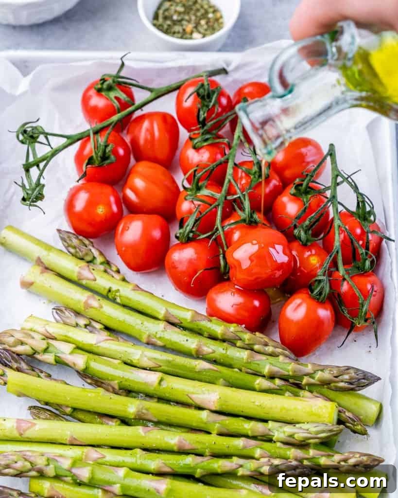 Placing cherry tomatoes on the vine and asparagus on a sheet pan.