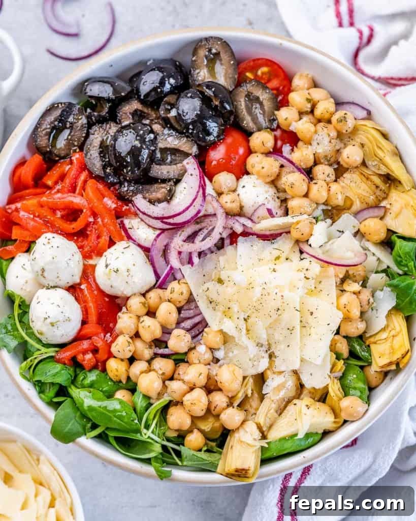 Classic Antipasto Salad 9 Top-down view of a generously sized, round white bowl brimming with a vibrant Antipasto Salad, featuring chickpeas, an assortment of colorful vegetables, and creamy cheese, ready to be enjoyed.