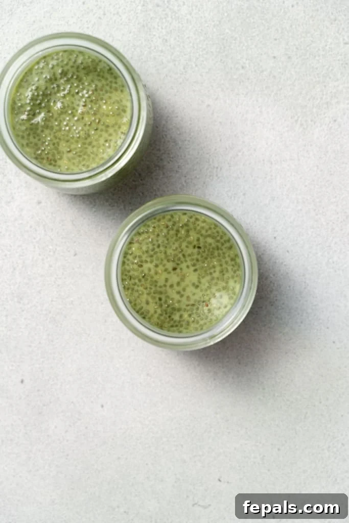 A top-down view of a glass jar, partially filled with the vibrant green matcha chia pudding mixture, illustrating the initial stage of portioning.