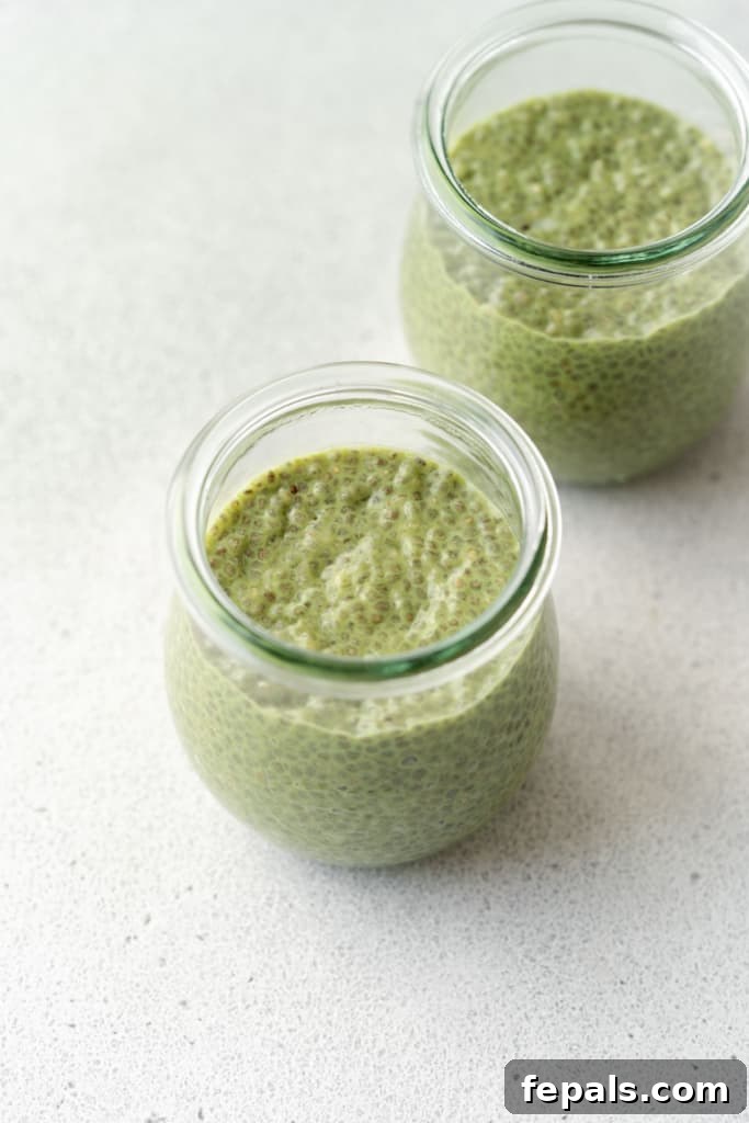A side view of a glass jar filled with fully set matcha chia pudding, showcasing its rich green color and creamy texture before toppings are added.
