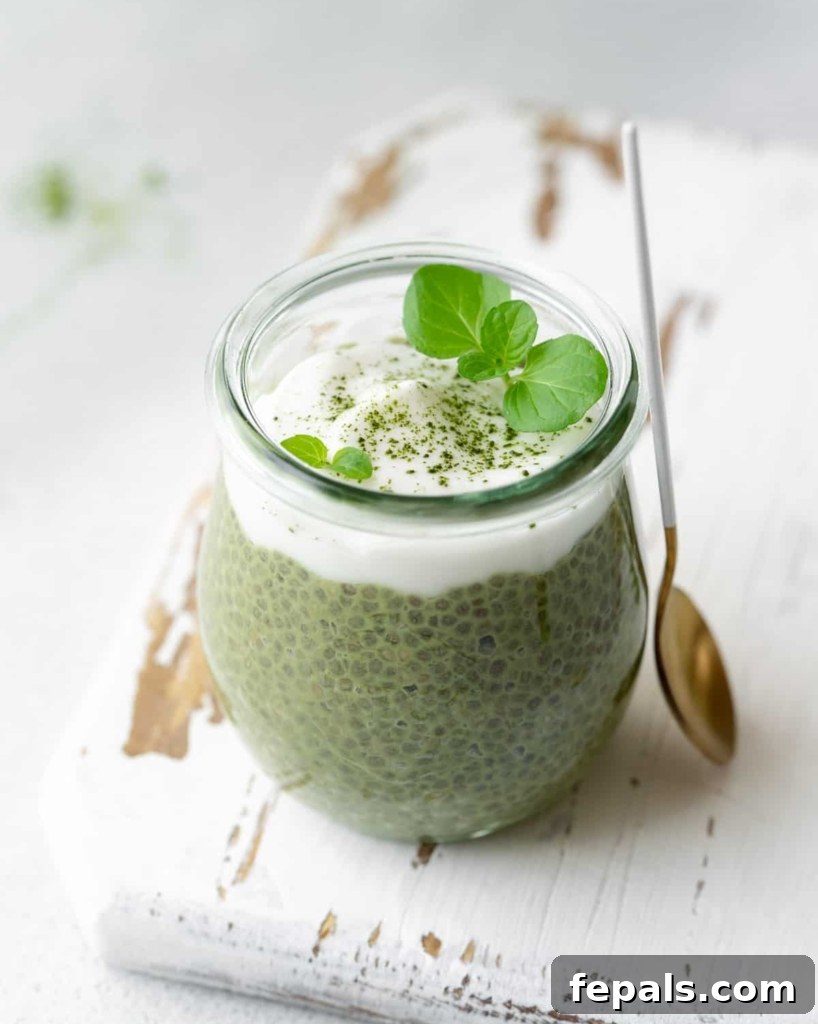 A serene side shot of a single jar filled with vibrant green matcha chia pudding, generously topped with creamy yogurt, signifying a delightful and healthy serving.