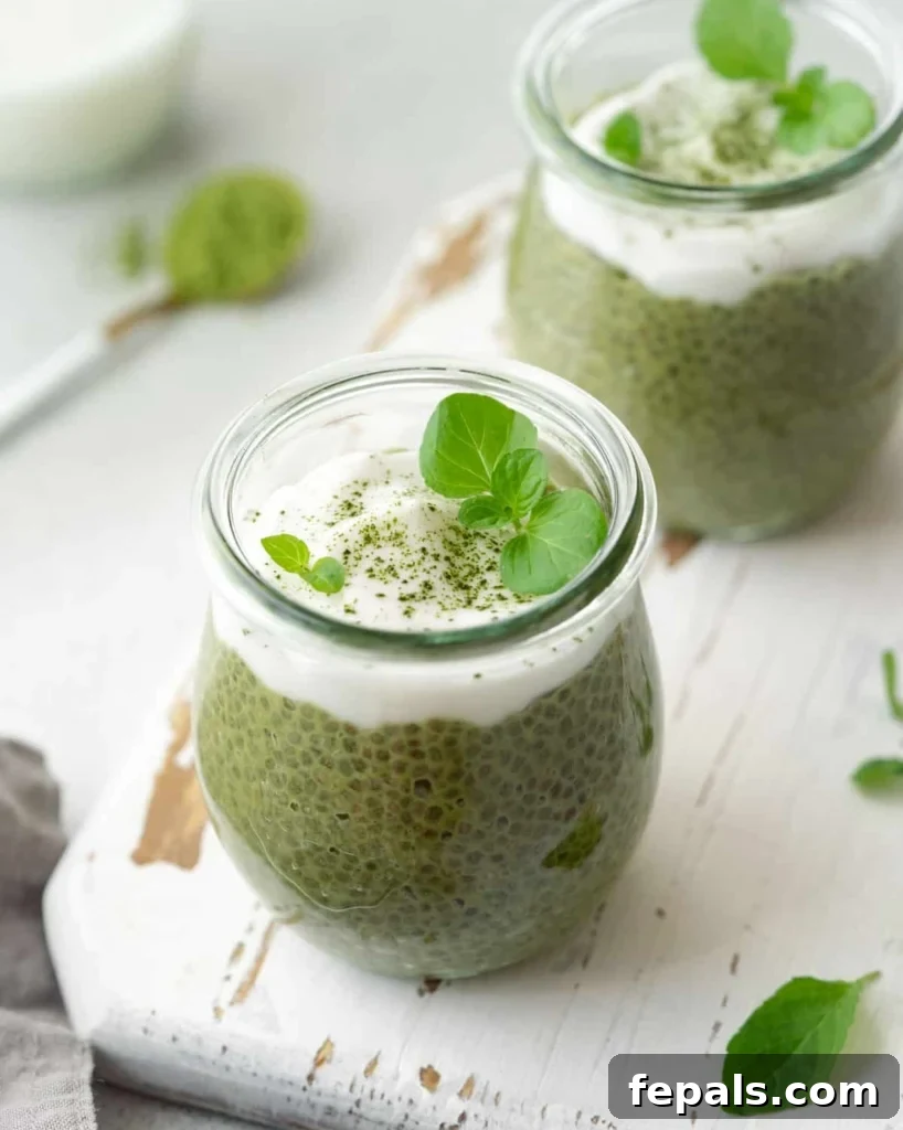 A close-up side view of a glass jar filled with luscious matcha chia pudding, beautifully adorned with a dollop of creamy yogurt or coconut whip, creating an inviting and healthy treat.