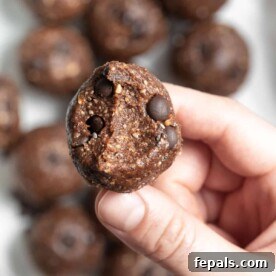 Hand holding an energy ball with a bite taken out, showing the inner texture.
