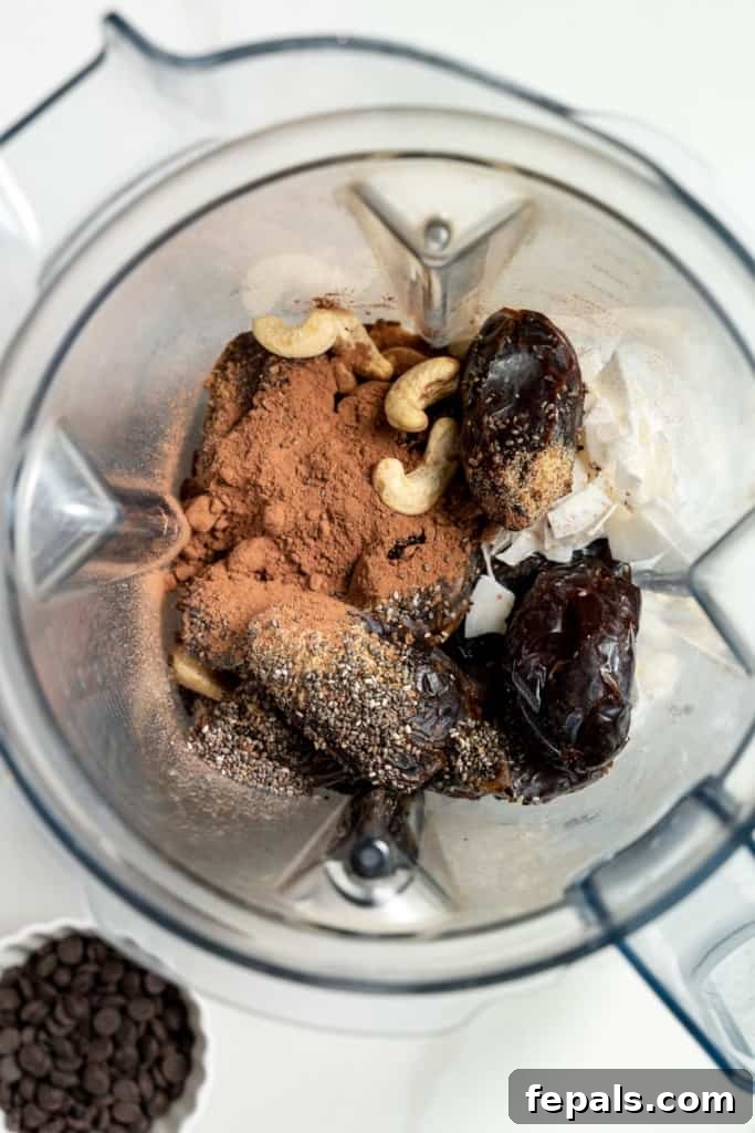 Decadent Double Chocolate Date Energy Bites 5 A blender being loaded with dates, nuts, and cocoa powder as primary ingredients.