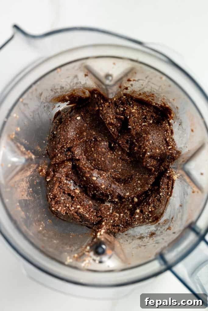 Decadent Double Chocolate Date Energy Bites 6 The blended mixture of dates, nuts, and cocoa powder inside a food processor, showing a smooth, consistent texture.