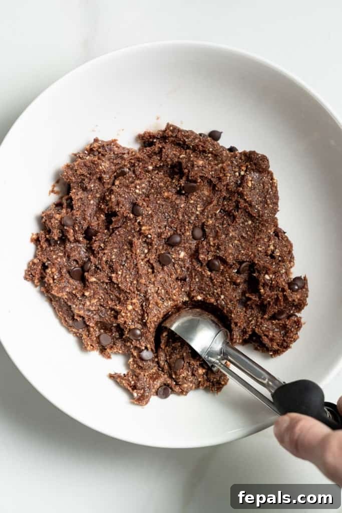 Decadent Double Chocolate Date Energy Bites 9 A cookie scoop being used to portion out the energy ball mixture.