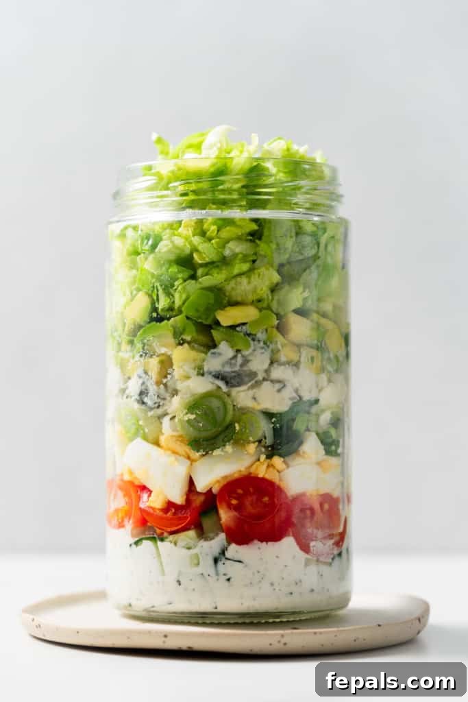 Plant-Powered Cobb Salad 11 Adding lettuce to a jar to make a salad in a jar.