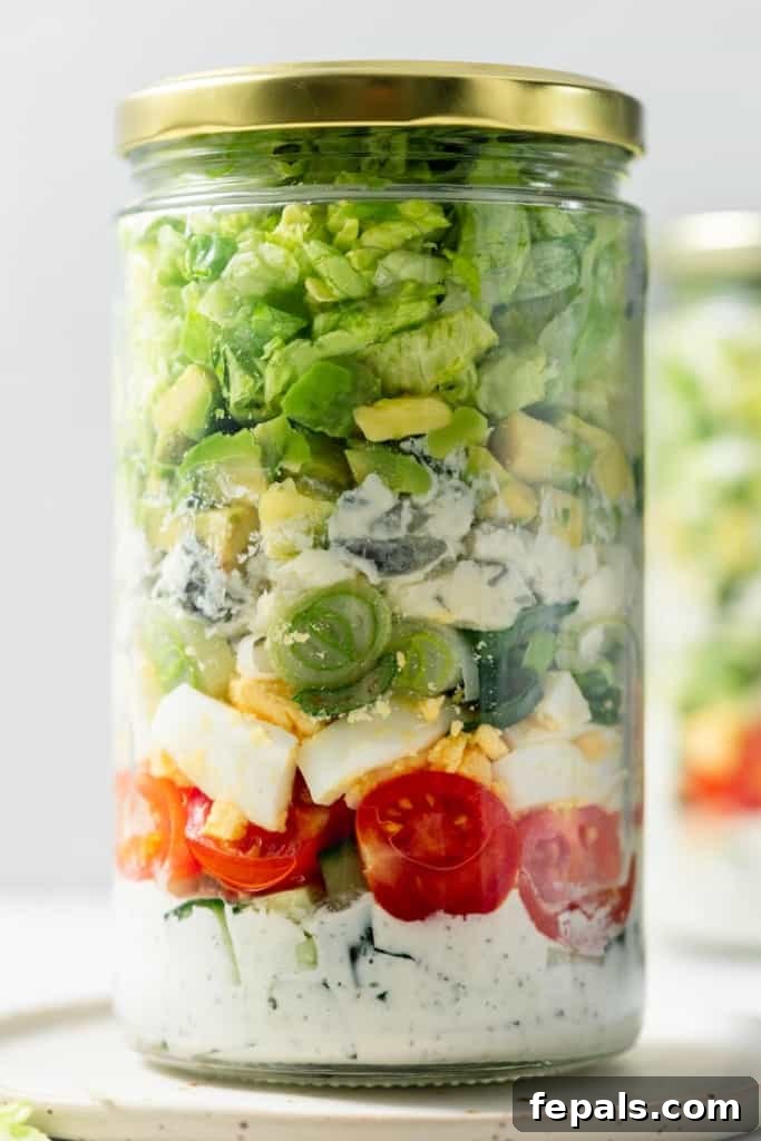 Plant-Powered Cobb Salad 3 Dressing, tomatoes, hard-boiled eggs, cheese and lettuce layered in a jar.