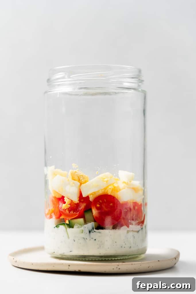 Plant-Powered Cobb Salad 8 Adding vegetables and hard-boiled eggs to a mason jar.
