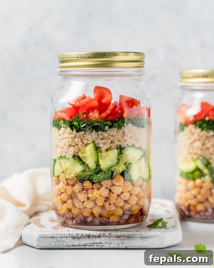 Refreshing Layered Chickpea Cucumber Jar 3 A perfectly layered quinoa and chickpea salad within a clear mason jar, showcasing its vibrant colors and fresh ingredients.