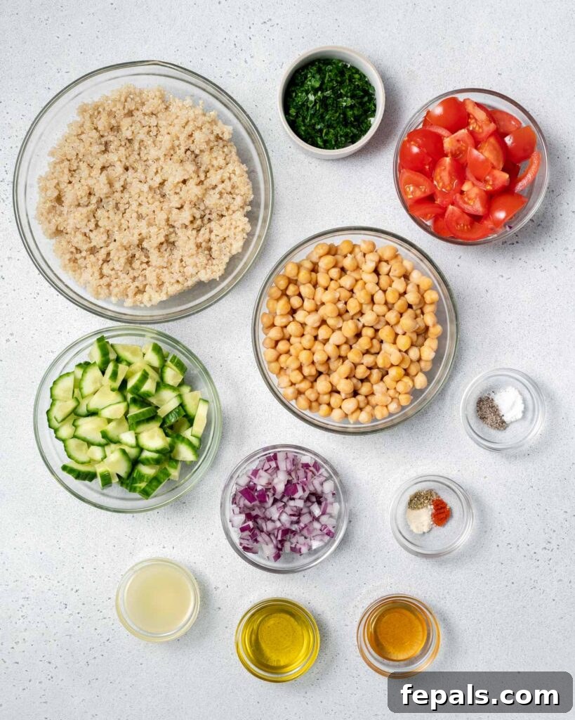 Refreshing Layered Chickpea Cucumber Jar 4 A collection of salad ingredients: cooked quinoa, chickpeas, diced cucumber, tomatoes, red onion, fresh herbs, olive oil, and seasonings, neatly arranged in small bowls.