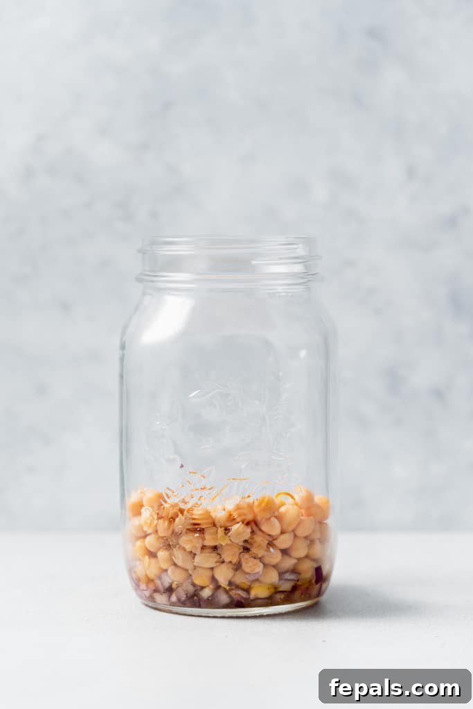 Refreshing Layered Chickpea Cucumber Jar 7 A mason jar with a layer of dressing at the bottom, followed by a generous layer of chickpeas.