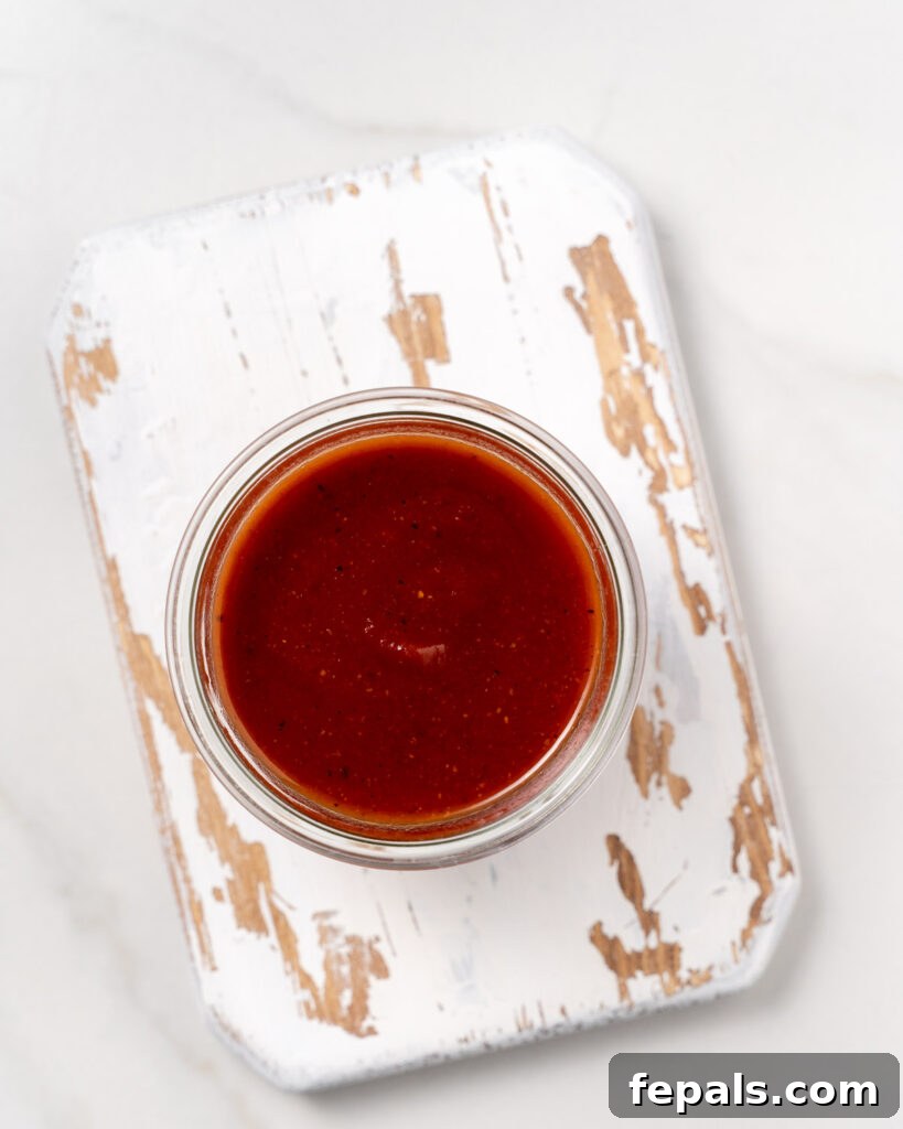 top view of a jar with homemade BBQ sauce over a wooden board 