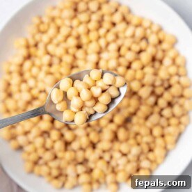 Your Guide to Perfectly Cooked Chickpeas 14 spoonful of cooked chickpeas over a plate full of chickpeas