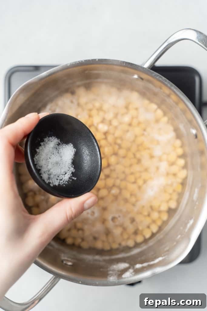 Your Guide to Perfectly Cooked Chickpeas 7 Adding salt to chickpeas in a pot of water.