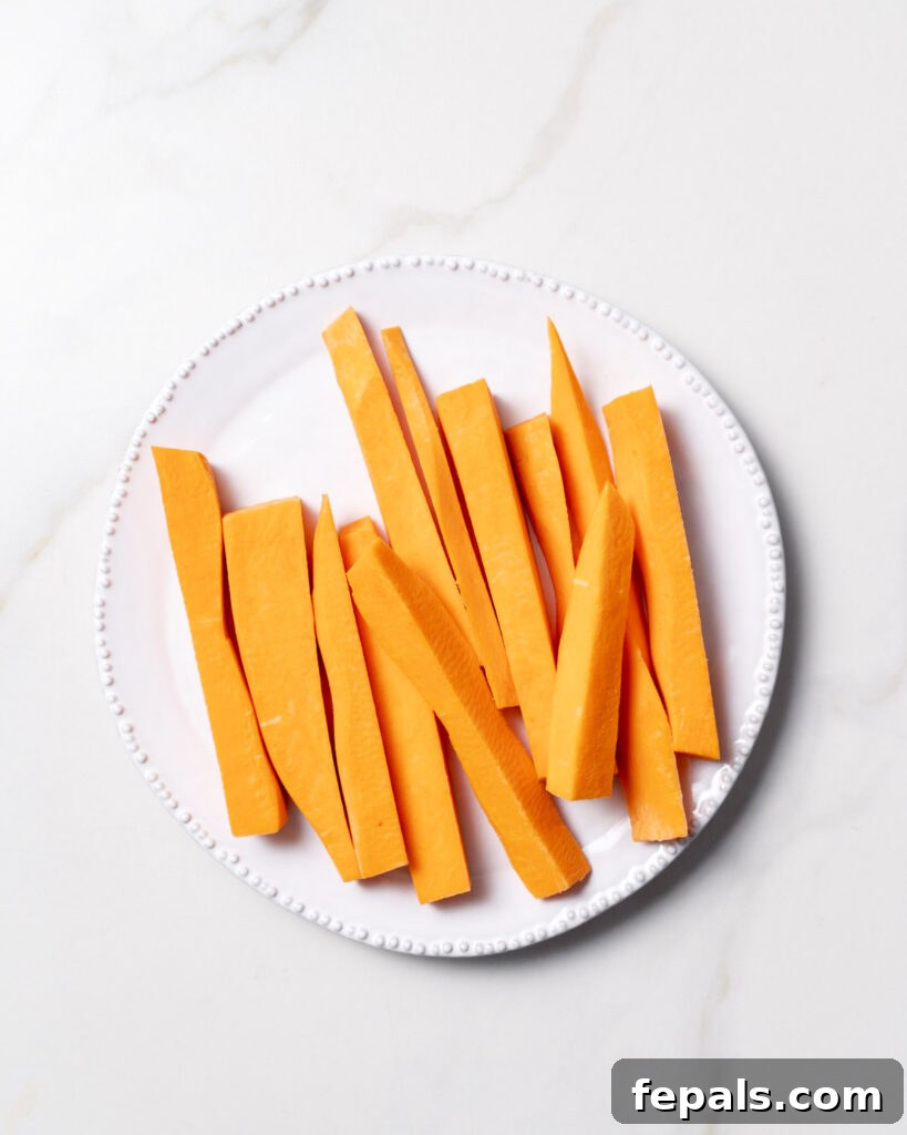 Sweet potatoes cut into sticks on a white plate.