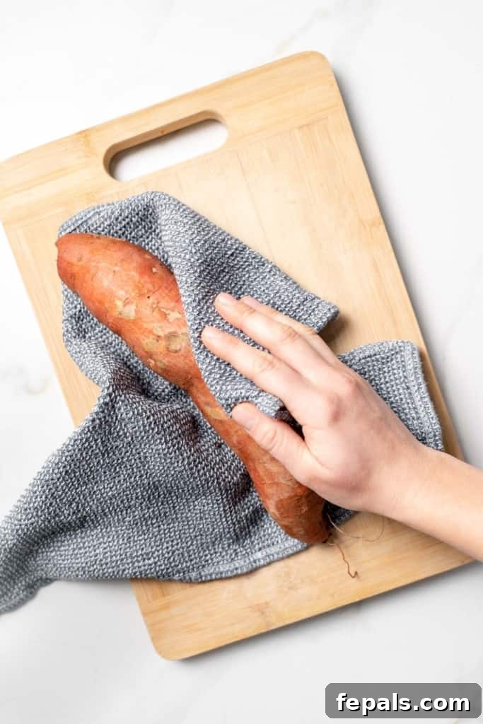 Using a kitchen towel to dry off a sweet potato.