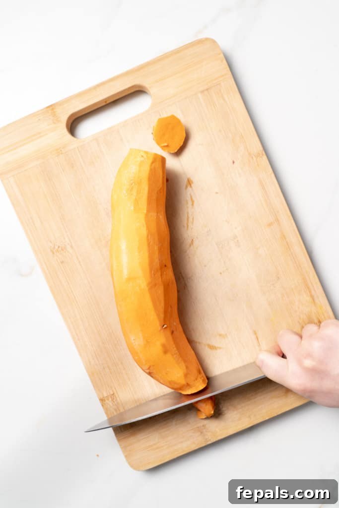 Using a knife to cut off the ends of a sweet potato.