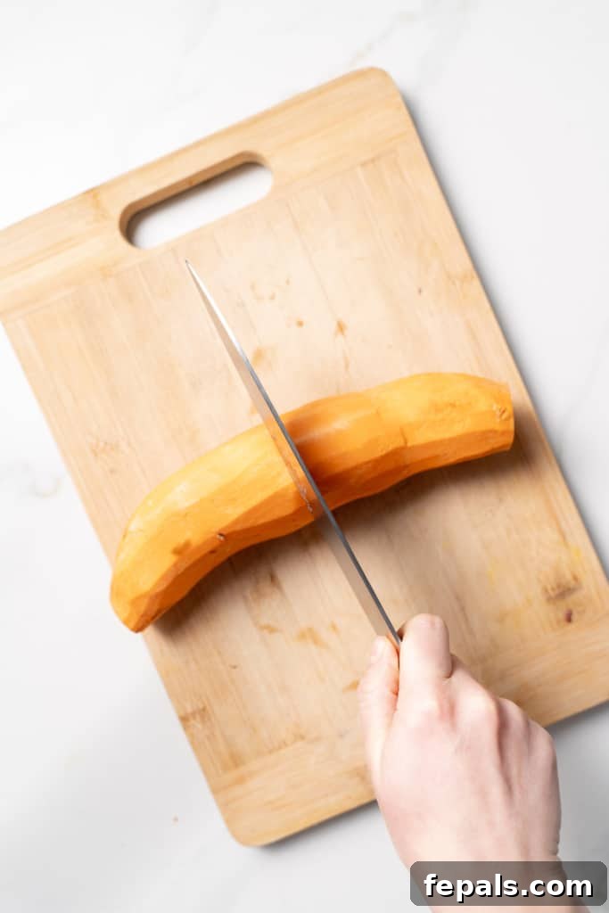 Cutting a peeled sweet potato in half.