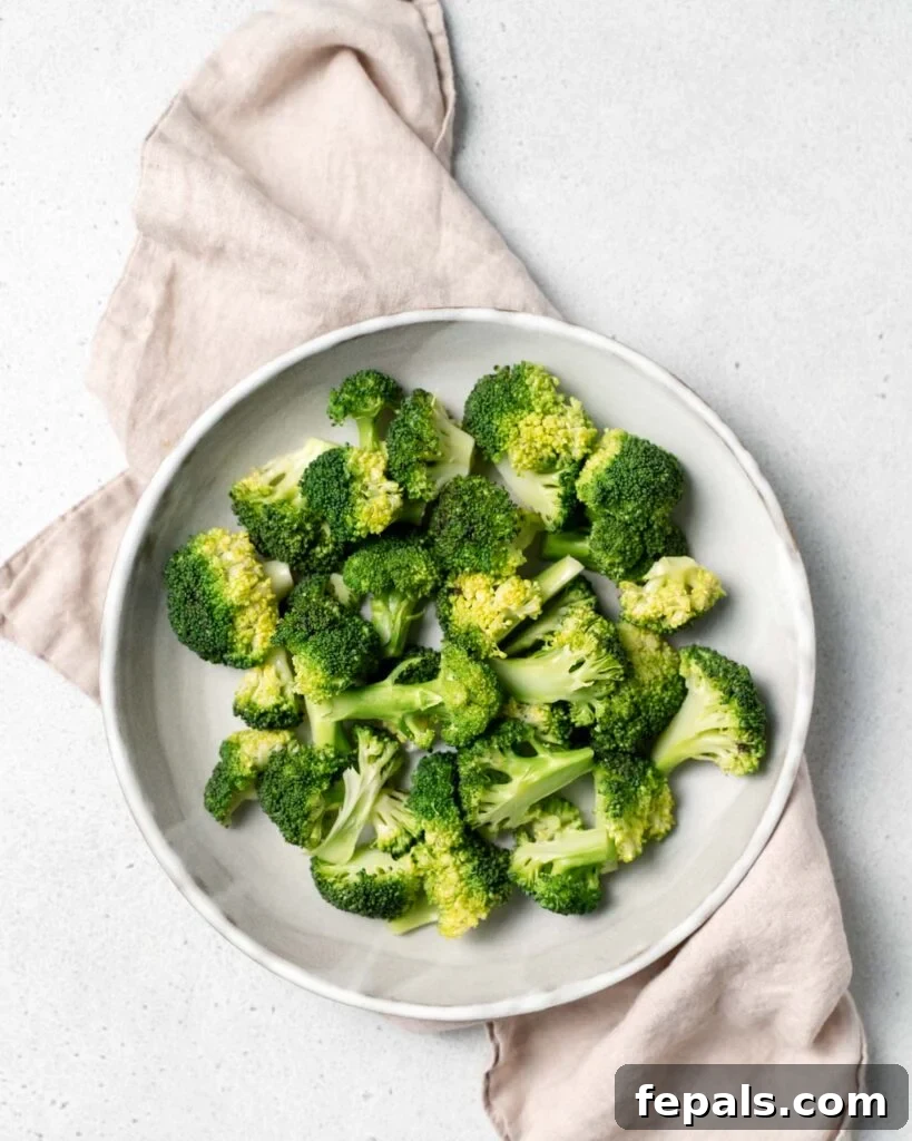 Stovetop Broccoli Perfection 15 A close-up of vibrant steamed broccoli florets artfully arranged on a pristine white round plate.