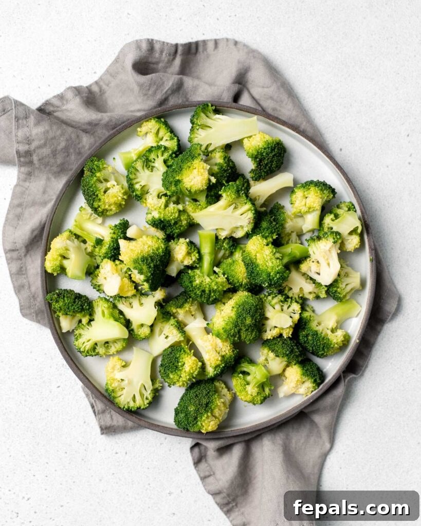 Perfect Stovetop Broccoli 18 Top view of cooked broccoli florets on a round plate over a gray cloth napkin.
