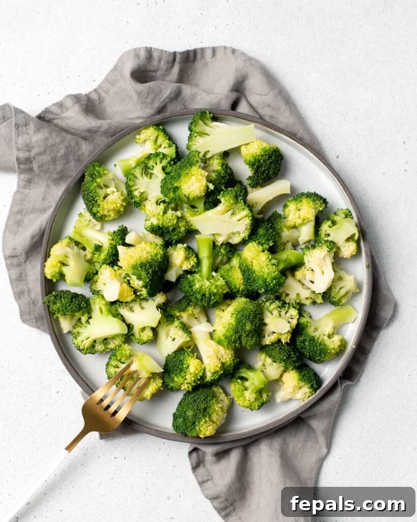 Stovetop Broccoli Perfection 3 A serving of perfectly cooked broccoli florets on a white plate, with a fork poised to pick up a piece.