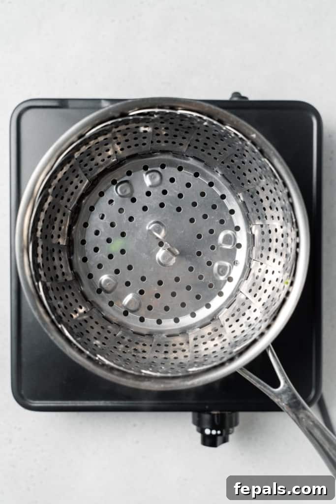 Stovetop Broccoli Perfection 6 A metal steamer basket being carefully lowered into a pot with simmering water.