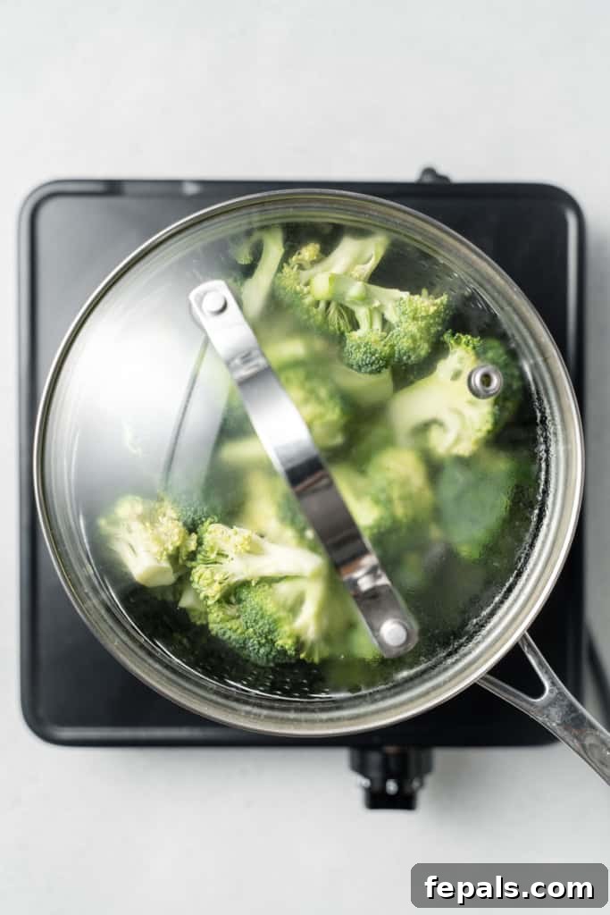 Perfect Stovetop Broccoli 7 Broccoli florets steaming in a covered pot.
