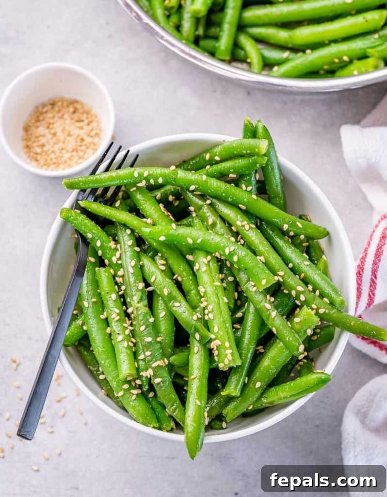Garlic Sautéed Green Beans 7 top view sauteed green beans in a white round bowl topped with sesame seeds