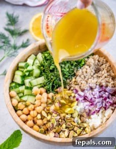 Pouring a lemon vinaigrette over a large salad.