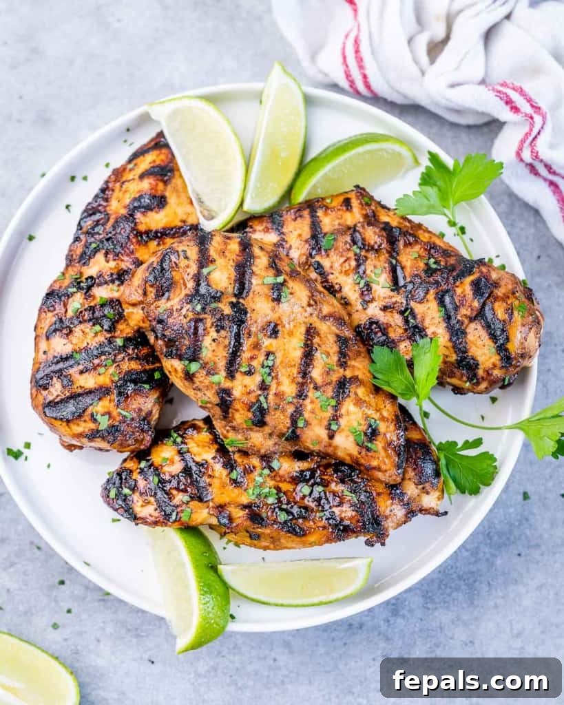 Crispy Honey Chipotle Chicken 2 Top view of grilled chicken breasts on a white plate with lime slices on the side for garnish.