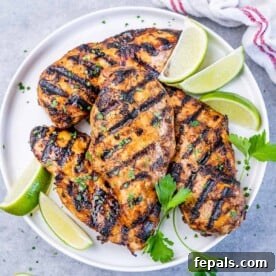 Crispy Honey Chipotle Chicken 11 top view of grilled chicken breasts on a white plate with lime slices on the side for garnish