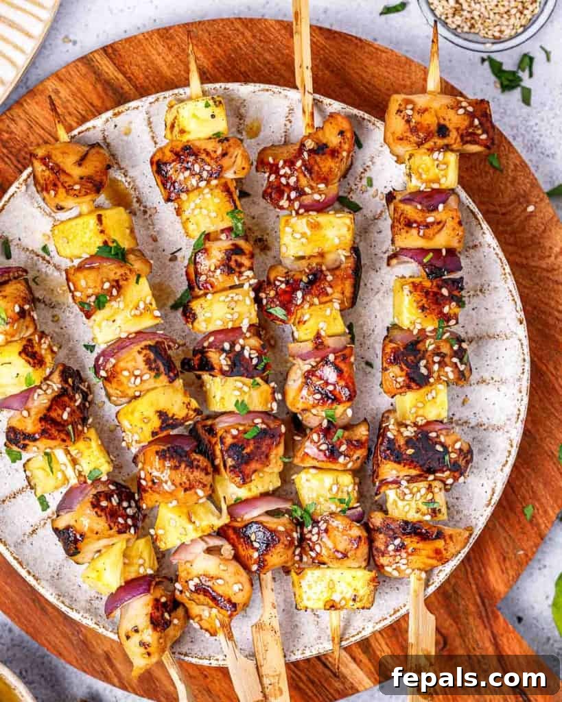 Grilled Umami Chicken Skewers 2 Top view of 5 grilled chicken skewers on a white round plate, garnished with sesame seeds and lime wedges.
