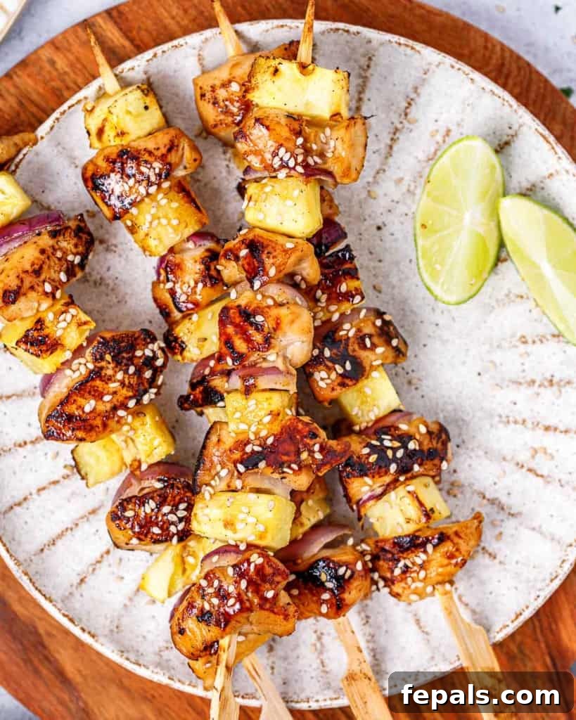 Grilled Umami Chicken Skewers 11 Grilled chicken skewers, vibrant with pineapple and red onion, displayed appetizingly on a plate.