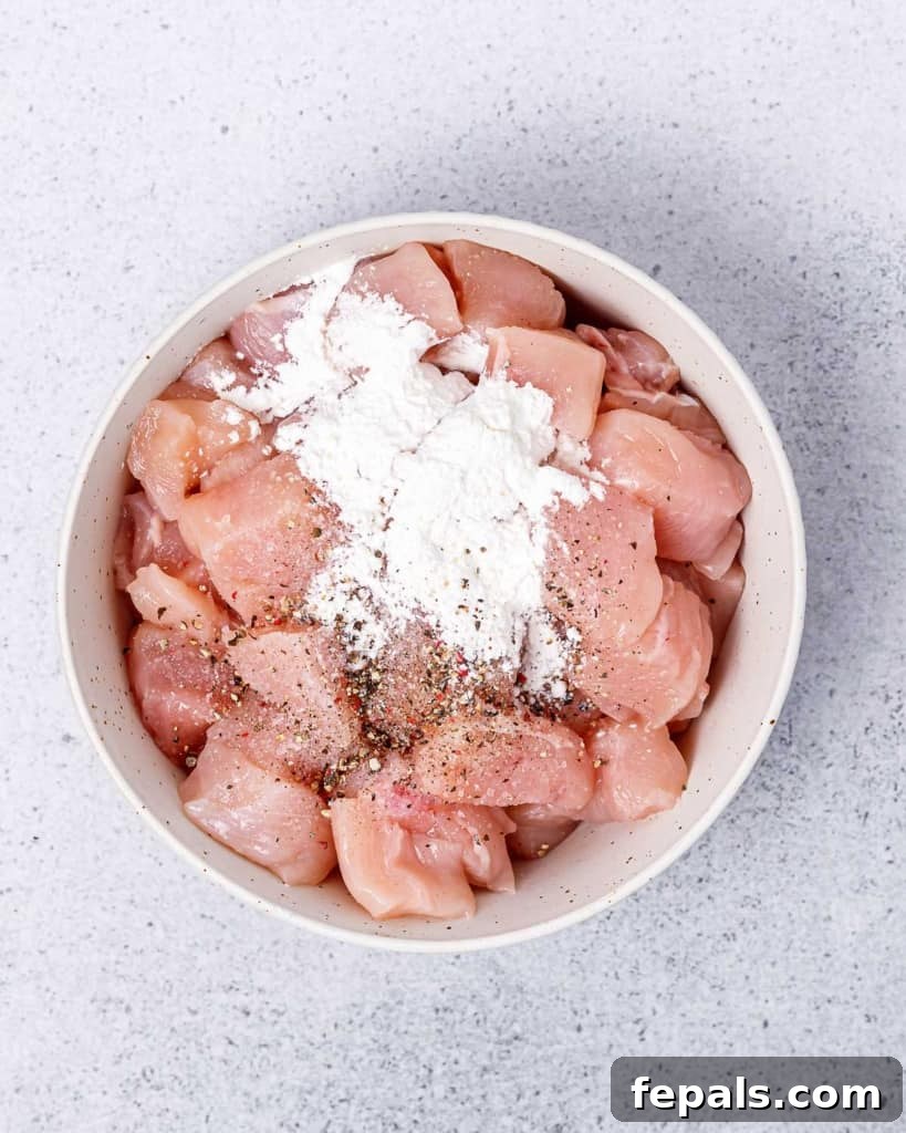 Grilled Umami Chicken Skewers 5 Raw chicken pieces uniformly tossed with salt, pepper, and cornstarch in a bowl.