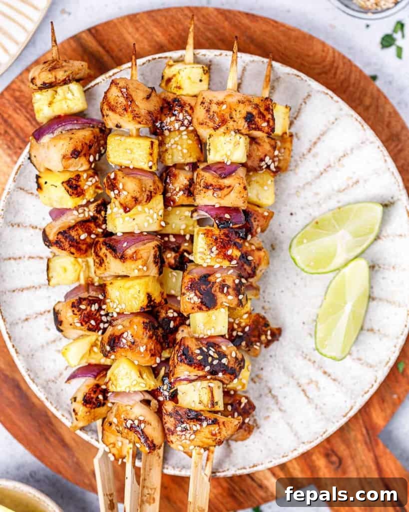 Grilled Umami Chicken Skewers 9 Grilled chicken skewers arranged on a white plate with fresh lime wedges for serving.