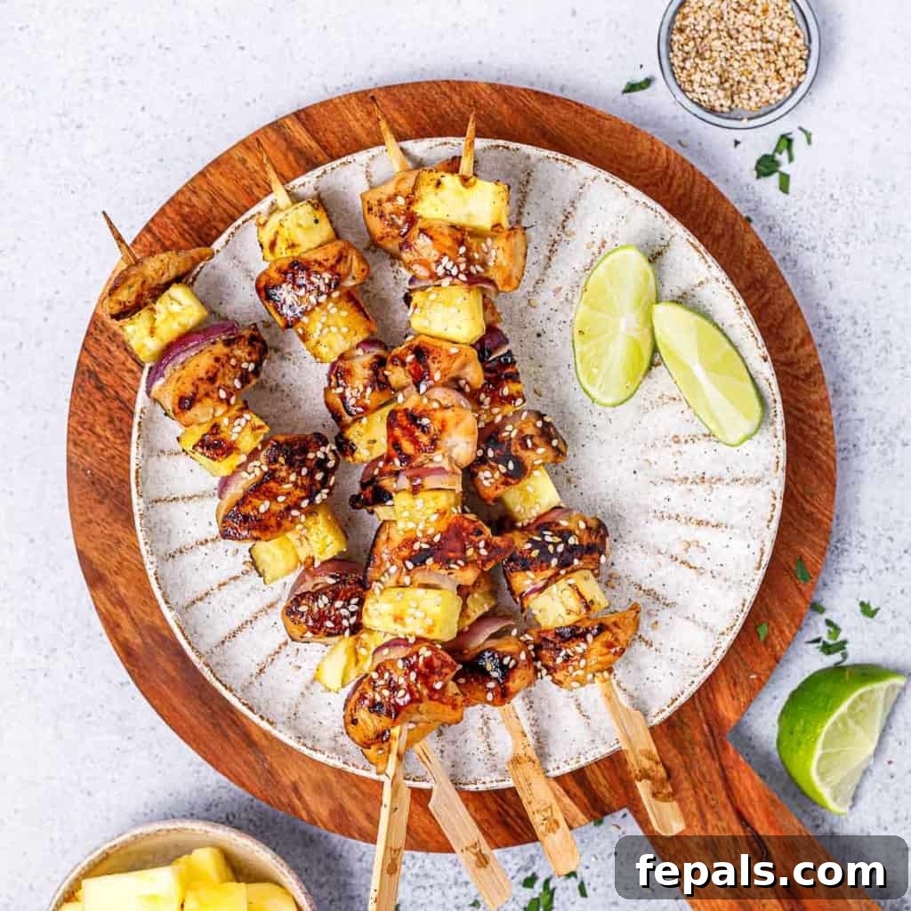 Grilled Umami Chicken Skewers 10 Image of 4 grilled chicken skewers on a round white plate with lime wedges on the side, ready to be enjoyed.