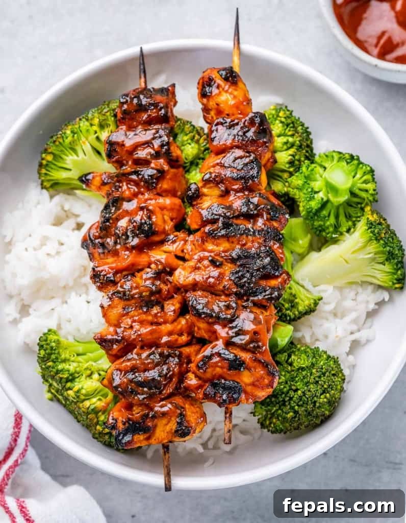 top view bbq chicken skewer served over a bowl of rice and sauteed broccoli in a round white bowl 