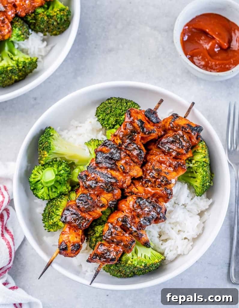 top view of 2 chicken skewers over a bowl or rice and broccoli