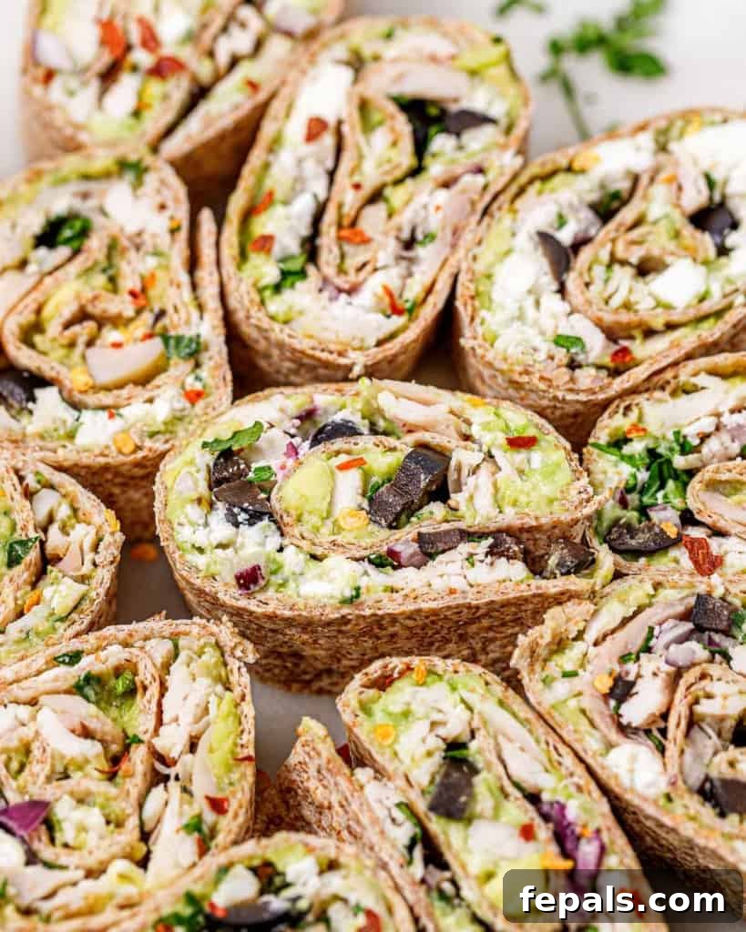 Close-up shot of chicken salad pinwheels, highlighting the creamy avocado, vibrant black olives, and shredded chicken inside.