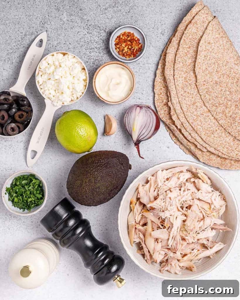 A collection of ingredients including shredded chicken, finely diced red onion, ripe avocado, crumbled feta cheese, and tortillas laid out on a surface.