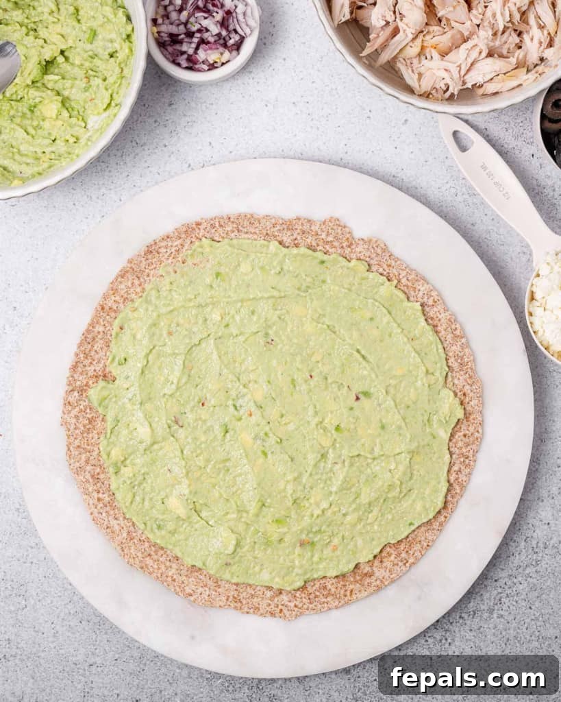 Carefully spreading the prepared avocado mixture evenly over a large tortilla, creating a flavorful layer.