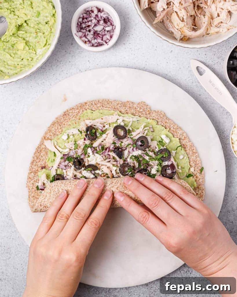 Tightly rolling a stuffed tortilla from one edge to the other, creating a compact log for slicing into pinwheels.
